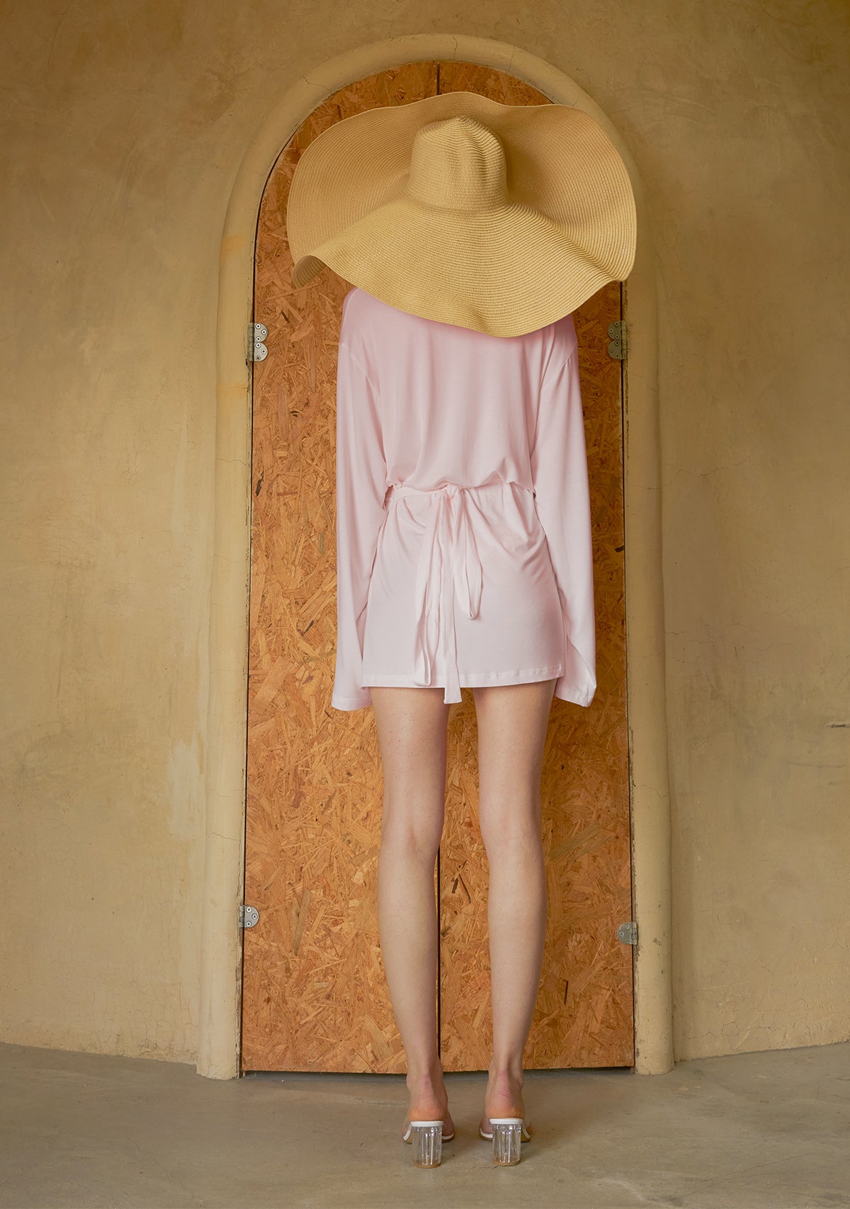 Pembe wrap gömlek ve geniş şapkalı model, arka plan çekim.